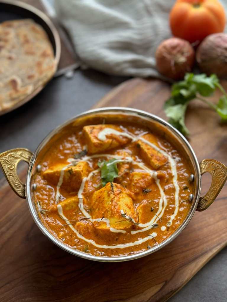paneer-masala with a roti on the side and onions, tomato and coriander leaf for decoration purpose