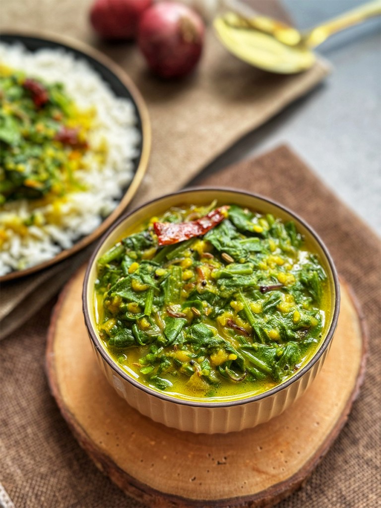 dal palak in a serving bowl and served with some steamed rice at the side